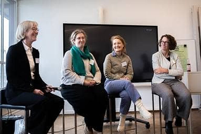 Vier Frauen sitzen auf hohen Barhockern und plaudern angeregt miteinander.